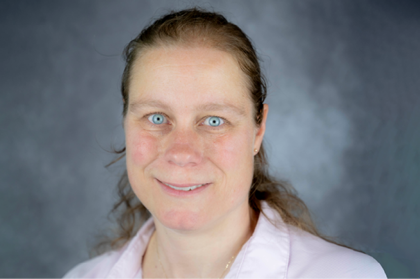 A white woman wearing a pink shirt against a green background