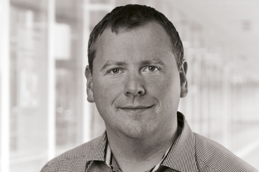 A mnochrome image of a white man with close cropped hair