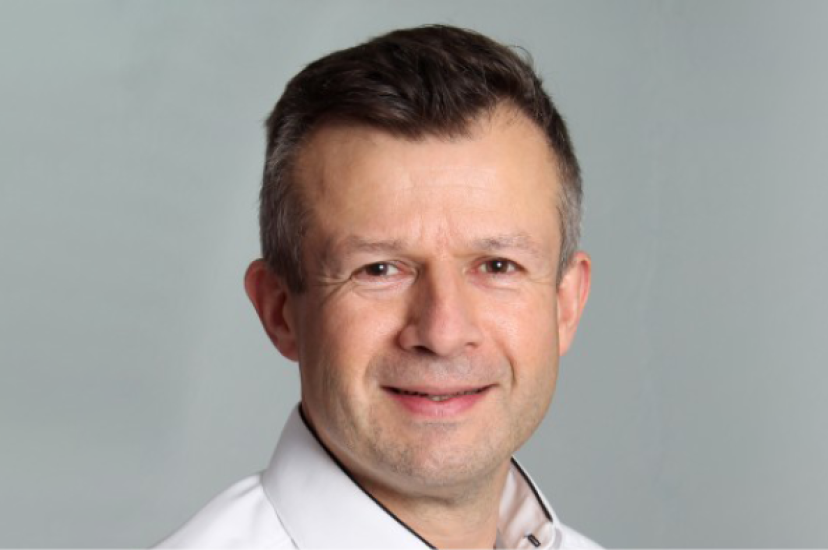 A white man with short brown hair. He iss wearing a white shirt 