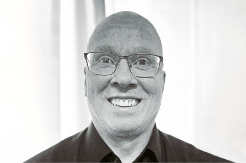 A white bald man wearing a dark shirt