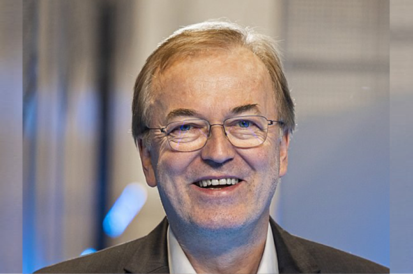 A white man with glasses and greying hair wearing a suit