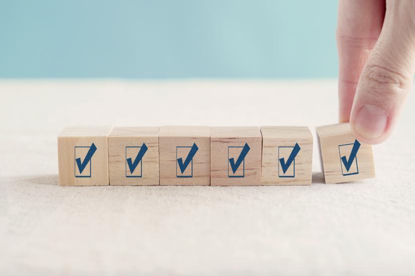 A hand placing the final check-mark block in a row of wooden cubes, representing participation in the 2026 Storage Survey on AI, HPC and data-intensive research.