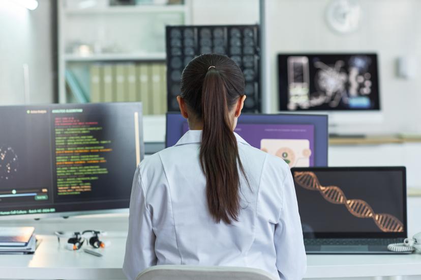 Researcher viewing four screens displaying scientific data dashboards