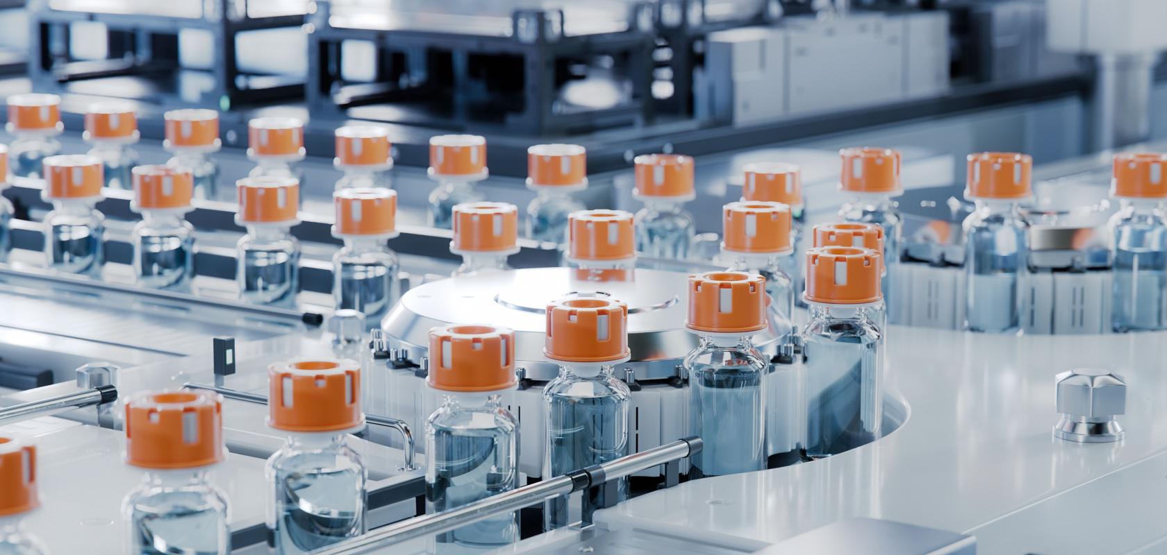 A series of clear glass drug vials with orange caps on a production line