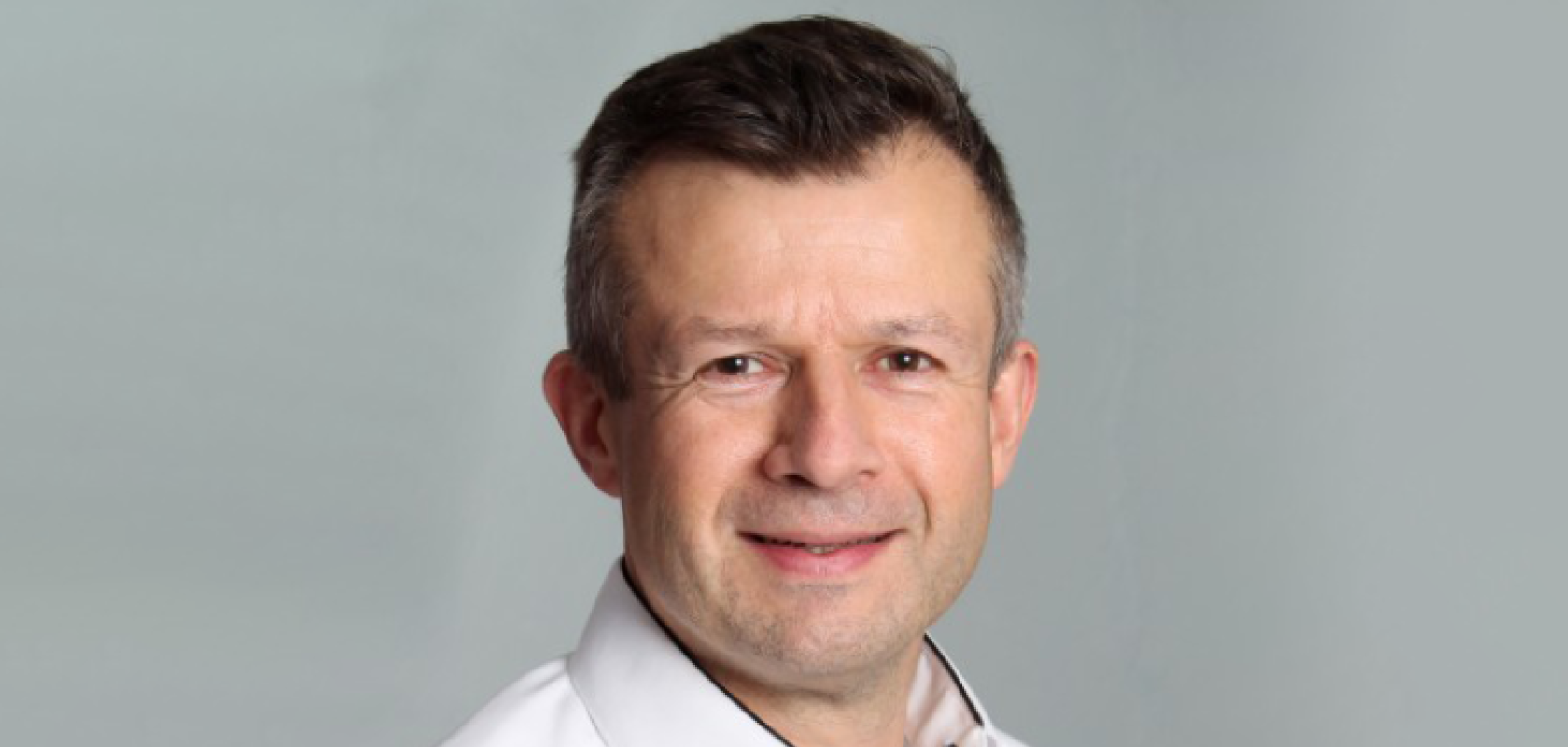 A white man with short brown hair. He iss wearing a white shirt 