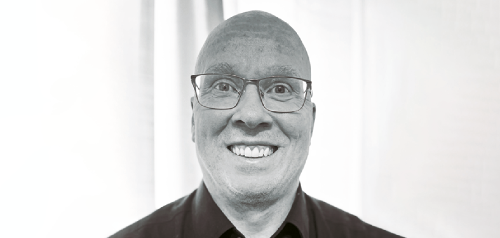 A white bald man wearing a dark shirt