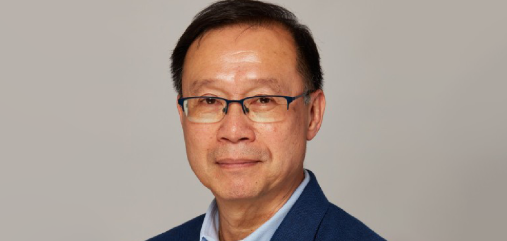 An Asian man with glasses and black hair wearing a blue suit