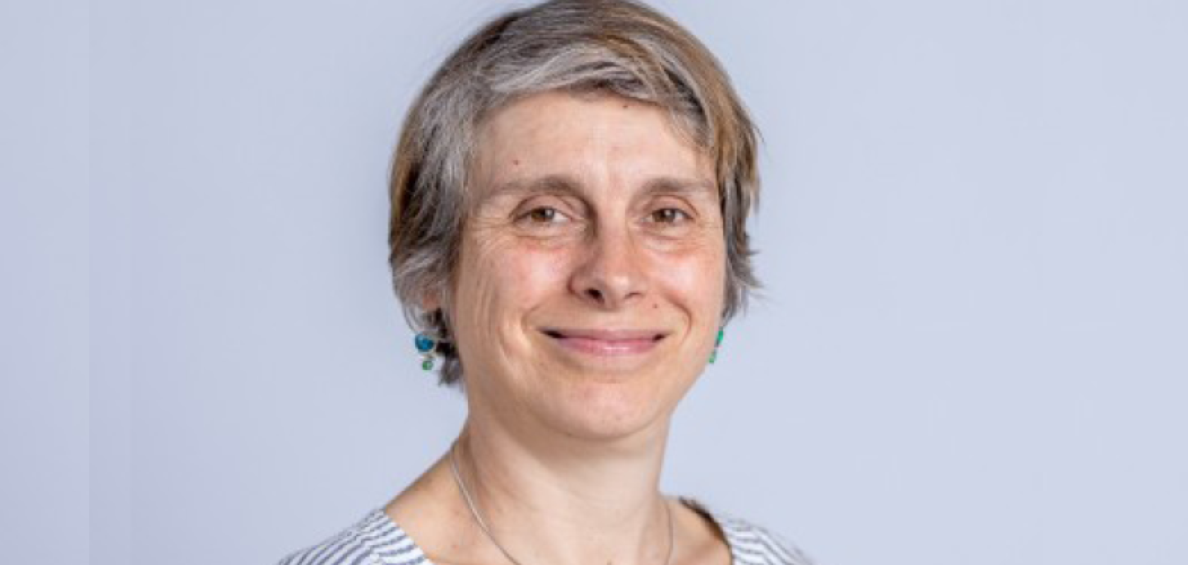 A white woman with short hair and wearing a striped shirt