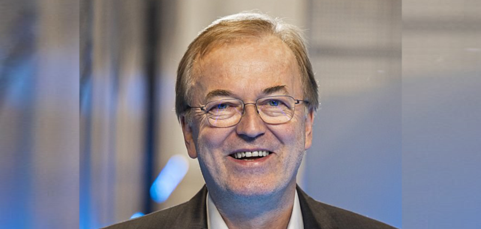 A white man with glasses and greying hair wearing a suit