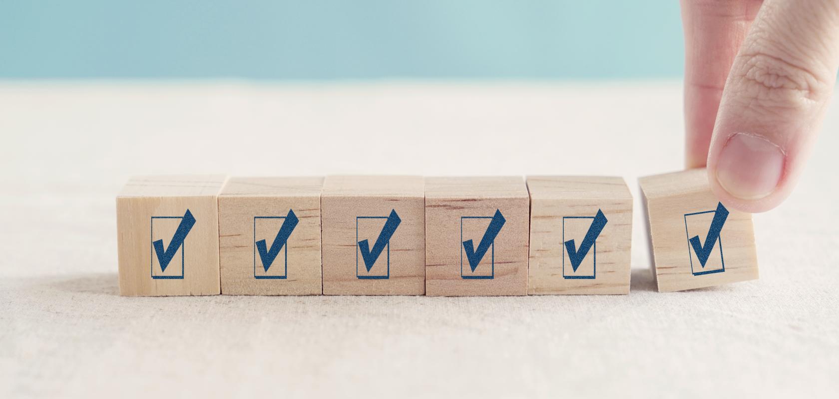 A hand placing the final check-mark block in a row of wooden cubes, representing participation in the 2026 Storage Survey on AI, HPC and data-intensive research.