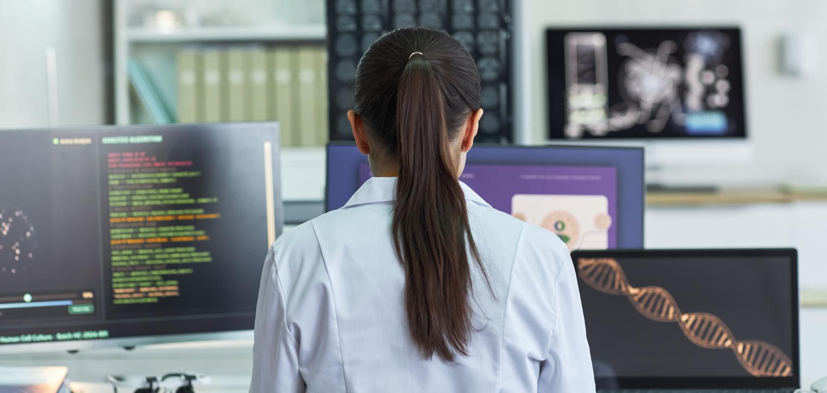 Researcher viewing four screens displaying scientific data dashboards