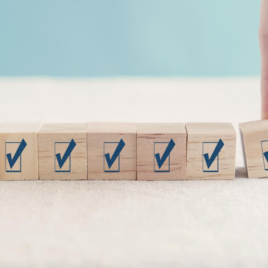 A hand placing the final check-mark block in a row of wooden cubes, representing participation in the 2026 Storage Survey on AI, HPC and data-intensive research.